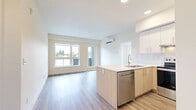 Located at 7701 E Saanich Rd in Saanichton, BC, this well-appointed two-bedroom, two-bathroom unit offers a thoughtfully designed single-level layout with modern finishes throughout. The open-concept kitchen and living area serves as the heart of the home, featuring a central island with a light wood base and white quartz countertop, white upper cabinetry, warm natural wood lower accents, a subway tile backsplash, stainless steel appliances, and recessed pot lighting. Light vinyl plank flooring flows seamlessly throughout the entire unit, lending a clean, cohesive aesthetic. Both bedrooms are bright and well-proportioned, with large windows that invite abundant natural light and offer views of the surrounding neighbourhood and mature trees. The primary bedroom includes a wall-mounted split heating and cooling unit for year-round comfort. The two bathrooms are finished with stone-look countertops, white cabinetry with brushed nickel hardware, large mirrors, and wood-look vinyl flooring. One bathroom features a glass-enclosed walk-in shower. Additional spaces include an entrance foyer, hallway, closet, and utility room, rounding out a practical and efficient floor plan suited for comfortable everyday living.