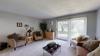 Located at 1930 E 86th St in Bloomington, MN, this one-bedroom, one-bathroom unit offers a practical and comfortable single-floor layout. The living room is a welcoming space featuring plush carpeting, a textured ceiling, and a sliding glass door that opens to a private balcony with views of mature trees and green outdoor surroundings, allowing natural light to fill the room. The combined kitchen and dining area features a galley-style kitchen equipped with white cabinetry, wood-accented upper cabinets, a double-basin sink, a dishwasher, and a coil-top electric range, all complemented by light wood-look flooring. The adjacent dining area provides a dedicated space for meals and is served by a ceiling fan overhead. The entry hallway includes a convenient storage closet and connects the main living areas efficiently. The bedroom is a comfortable retreat with carpeted floors, a large window overlooking the outdoors, a textured ceiling, and a wide closet with louvered sliding doors. The full bathroom features a tiled tub and shower surround, a vanity with a single sink, and clean, functional finishes. Throughout the unit, a neutral gray color palette creates a cohesive and calm ambiance.