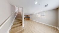 Located at 711 W 32nd St in Austin, TX, this two-story, 2-bedroom, 2-bathroom home offers a well-designed layout across two floors. Light wood-style flooring flows consistently throughout, complementing the neutral warm-gray walls and bright white trim for a clean, cohesive aesthetic.

The main floor houses the combined kitchen and living area. The kitchen is a standout feature, equipped with warm wood cabinetry, dark stone-look countertops, a peninsula with pendant lighting, and black and stainless steel appliances including a range, microwave, and dishwasher. The open living area benefits from recessed lighting and multiple windows that invite natural light.

Upstairs, both bedrooms are generously proportioned, each featuring ceiling fans with light fixtures and multiple windows dressed with white horizontal blinds, providing views of the surrounding neighborhood greenery. The primary bedroom includes an en-suite bathroom, while the second bathroom is accessible from the hallway. The bathrooms feature tile-surround soaking tubs and wood vanities. A staircase connects the two floors, with the upper level also featuring a hallway that links the bedrooms and bathrooms. Throughout the home, the design is modern, clean, and functional — well-suited for comfortable living in central Austin.