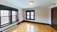 Located at 706 S Ninth St in Minneapolis, MN, this well-maintained single-floor unit blends classic architectural character with modern updates. Throughout the living spaces, warm honey-toned hardwood floors are complemented by rich, dark wood trim and baseboards, creating a timeless aesthetic. Multiple windows with bold dark frames allow natural light to pour in while offering views of the surrounding urban neighborhood.

The open living area is spacious and versatile, with clean white walls and a neutral palette that makes the space feel bright and inviting. Baseboard and panel heaters are positioned beneath the windows, ensuring comfort throughout the seasons. A dedicated entryway area includes a built-in electrical panel and provides a functional transition into the main living space.

The kitchen is appointed with floor-to-ceiling dark espresso cabinetry offering generous storage, light-toned countertops, a stainless steel undermount sink, a glass tile backsplash, and stainless steel appliances. The layout makes efficient use of the available space with a smart corner configuration.

The bathroom features a glass-enclosed shower with white subway tile, a wood-toned wall-mounted storage cabinet, a vanity with an integrated sink, and light blue walls that lend a calm, clean ambiance. The unit's cohesive use of dark wood accents ties each room together into a polished, unified living environment.