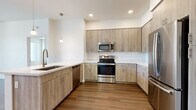 Located at 222 W Boston St in Chandler, Arizona, this modern 2-bedroom, 3-bathroom residence offers a well-designed single-floor layout with contemporary finishes throughout. The open-concept kitchen is a standout feature, showcasing light wood-tone cabinetry that extends to the ceiling, crisp white quartz countertops, a large kitchen island with an undermount sink, and a full suite of stainless steel appliances including a range, built-in microwave, dishwasher, and refrigerator. Warm hardwood-style flooring runs throughout the main living areas, complemented by recessed lighting and modern pendant fixtures. The living area is bright and airy, with a ceiling fan and sliding glass doors that open to an outdoor patio with neighborhood views. Both bedrooms are carpeted and receive ample natural light through large windows with vertical blinds, and each is served by its own dedicated closet. The primary bedroom connects to a spacious en-suite bathroom featuring a dual-sink vanity with light wood cabinetry, white quartz counters, and hardwood-style flooring. Additional bathrooms feature tub-shower combinations, wood-toned vanities, and clean white finishes, maintaining a consistent modern aesthetic throughout the home.