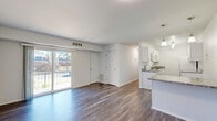 This 2-bedroom, 1-bathroom home in Richmond, Virginia offers a well-organized, single-floor layout with a clean, modern aesthetic throughout. Durable hardwood-style flooring runs consistently across all living spaces, providing a cohesive and easy-to-maintain finish.

The open-concept living, dining, and kitchen area forms the heart of the home. The kitchen is outfitted with crisp white shaker-style cabinetry, granite-look countertops, white appliances, and a peninsula that opens to the living space. A stylish multi-bulb chandelier adds a contemporary touch. The living room is bright and airy, featuring a sliding glass door that opens to a private outdoor balcony, allowing for ample natural light and outdoor views.

Both bedrooms are well-proportioned with neutral white walls and hardwood-style flooring. The primary bedroom includes a dedicated closet, while the second bedroom benefits from a natural light window. The home includes a total of four closets, offering generous storage throughout.

The bathroom features a full tub-shower combination with white tile surround and a built-in niche for added storage convenience. A dedicated laundry area and a connecting hallway complete the functional layout of this tidy, move-in-ready home.
