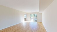 This single-floor residence offers a clean, functional layout designed for comfortable everyday living. Warm light hardwood flooring flows throughout the main living areas and bedrooms, creating a cohesive and inviting atmosphere. The spacious living room is a standout feature, bathed in natural light streaming through a large sliding glass door that opens onto a private balcony overlooking lush greenery — an ideal spot for relaxing or entertaining.

The galley-style kitchen is thoughtfully designed with rich mahogany-toned cabinetry lining both walls, granite countertops, tile flooring, and a full suite of stainless steel appliances including a gas range, built-in microwave, dishwasher, and refrigerator. Ample upper and lower cabinet storage makes this kitchen as practical as it is attractive.

The bedrooms are generously sized, each featuring hardwood floors, neutral walls, and windows that invite natural light. Several rooms include closets with sliding or paneled doors, offering practical storage solutions.

Two bathrooms serve the residence, each finished consistently with tile flooring, mahogany vanities topped with granite countertops, and mirrored medicine cabinets. The neutral color palette carried throughout the entire space lends a bright, airy feel, making it move-in ready and easy to personalize.