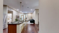 Located in Houston's vibrant Montrose neighborhood, this well-appointed 2-bedroom, 2-bathroom residence offers a thoughtfully designed single-level layout that balances style and functionality. The open-concept living area features rich hardwood flooring, crown molding with gold accents, and large windows with a glass-panel door that invite natural light and provide access to an outdoor patio. The kitchen is equipped with warm cherry wood cabinetry, dark granite countertops, stainless steel appliances, a tile backsplash, and a peninsula island with seating beneath stylish pendant lighting. The adjacent dining area showcases parquet hardwood flooring and ample wall space ideal for artwork. The primary bedroom includes plush carpet, a decorative feature wall, a ceiling fan, and a private en-suite bathroom with a dual-sink vanity, dark granite countertops, rich wood cabinetry, and a soaking tub. A walk-in closet with wire shelving provides generous storage. The second bedroom and bathroom offer equally refined finishes. A dedicated built-in office nook with a granite desk surface and overhead shelving adds a practical workspace. Two closets and a hallway complete the layout, making this residence a refined and functional home in the heart of Houston.