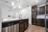 This 1,050-square-foot, single-story unit at 1351 Federal Hwy in Boynton Beach, FL offers a well-designed 2-bedroom, 2-bathroom layout with modern finishes throughout. The open-concept living area flows seamlessly into the kitchen, featuring rich dark wood cabinetry, white quartz countertops, stainless steel appliances including a range, microwave, and refrigerator, and wood-look plank flooring that extends throughout the unit. The bright living room benefits from natural light through double windows with blinds and elevated ceilings with a ceiling fan. The primary bedroom spans 160 square feet and includes its own en-suite bathroom with a dual-sink vanity, dark wood cabinetry, quartz countertop, and a glass-enclosed walk-in shower. A spacious walk-in closet with wire shelving provides generous storage. The second bedroom is equally well-appointed with access to a full bathroom featuring a tub-shower combination, tiled surround, and a single-sink vanity. A second walk-in closet with wire shelving serves additional storage needs. The dedicated laundry room houses a full-size washer and dryer alongside a water heater, completing this functional and move-in-ready home.