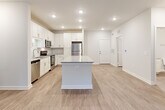 Located in Jonesboro, GA, this well-appointed 2-bedroom, 2-bathroom single-floor residence offers a clean, modern aesthetic throughout. The open-concept kitchen and living area serves as the heart of the home, featuring crisp white shaker cabinetry, a subway tile backsplash, stainless steel appliances, and a central island topped with granite countertops — ideal for both cooking and casual entertaining. Recessed lighting illuminates the space, complemented by a ceiling fan in the living area. Large windows along the living room's exterior wall invite abundant natural light and offer views of lush greenery outside. Consistent wood-style plank flooring runs throughout the entire residence, tying the spaces together with a warm, cohesive look. Both bedrooms are bright and neutral, with natural light filtering through window blinds. Each bedroom benefits from its own dedicated closet with wire shelving systems that maximize storage. The two bathrooms are finished with granite countertops and tiled shower/tub surrounds. A utility room and hallway complete the functional layout. The space's neutral color palette, modern finishes, and thoughtful design make it a comfortable and versatile place to call home.