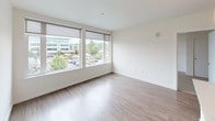 Located at 311 4th Ave N in Kent, Washington, unit 309 is a single-floor residence offering a well-designed, contemporary living space. The open-concept kitchen and living area form the heart of the unit, featuring warm hardwood-style flooring throughout. The kitchen is appointed with dark espresso cabinetry, light quartz countertops, a subway tile backsplash, stainless steel appliances including a range and refrigerator, and a peninsula with pendant lighting and an undermount sink—providing both functional workspace and a natural gathering point.

The living area benefits from expansive windows fitted with roller shades, allowing generous natural light and views of the surrounding neighborhood. The bedroom features plush carpeting, a ceiling fan with light fixture, a large window framing outdoor views, and a closet with sliding doors. A hallway connects the bedroom to the bathroom, maintaining a practical flow throughout the unit.

The bathroom is outfitted with hardwood-style flooring, a dark vanity with a tile-accented backsplash, a full soaking tub with shower, and accessibility grab bars. The clean white walls and modern fixtures contribute to a bright, neutral aesthetic throughout the unit, creating a cohesive and move-in ready environment.