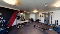 Located at 515 W Colorado St in Glendale, California, this fitness center is a comprehensively outfitted facility designed to support a wide range of workout routines. The space is contained on a single floor and benefits from a practical, open layout that maximizes usability and flow between equipment zones.

The interior features durable rubber flooring throughout, providing cushioning and traction suited for both strength training and cardio activity. Equipment includes an Endurance R300 rowing machine, Spirit treadmill, adjustable weight benches, a multi-functional cable machine with pull-up station, a full rack of dumbbells, medicine balls in varying weights, and a stability ball. A large wall-spanning mirror along one side of the room enhances the sense of space and allows users to monitor their form during exercise.

Ambient lighting is provided by flush-mounted drum fixtures, creating a well-lit environment. A window along one wall introduces natural light and an exterior view. Bold motivational graphics, including the phrases "Eat Sleep Train Repeat" and "Impossible Is Nothing," are painted directly onto accent walls in a dynamic color scheme of navy, red, blue, and gold. A wall-mounted flat-screen television adds a media element to the space. The overall design is modern, energetic, and purpose-driven.