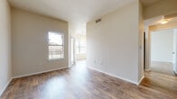 This single-floor unit offers a clean, modern layout with wood-look plank flooring carried consistently throughout every room, lending a cohesive and low-maintenance aesthetic. The open living areas are defined by neutral beige walls, crisp white baseboards, and vaulted ceilings that amplify the sense of space. Multiple windows fitted with horizontal blinds invite generous natural light, creating a bright and airy atmosphere across the main living and bedroom areas.

The galley-style kitchen is well-equipped, featuring rich dark wood cabinetry, black appliances including a refrigerator, range, and dishwasher, a mosaic tile backsplash, light stone-look countertops, and track lighting overhead. A hallway connects the kitchen to the remainder of the unit seamlessly.

The bedrooms are generously proportioned, each benefiting from large windows with exterior views and ceiling fans for comfort. The bathroom includes a full tub-shower combo with white tile surround, a wood-toned vanity, and wood-look tile flooring that ties into the overall design scheme.

A dedicated in-unit laundry closet houses a full-size side-by-side washer and dryer, adding significant convenience. The thoughtful layout, consistent finishes, and abundant natural light make this a highly functional and comfortable single-level living space.