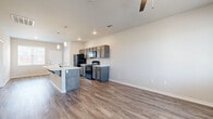 This single-story unit offers a thoughtfully arranged floor plan across two bedrooms and two bathrooms. The open-concept living and kitchen area serves as the heart of the space, featuring warm wood-look vinyl plank flooring that extends throughout the main living zones. A ceiling fan overhead enhances airflow and comfort, while multiple windows allow natural light to fill the room from several angles, creating a bright and welcoming atmosphere.

The kitchen is equipped with dark-toned cabinetry, black appliances including a refrigerator, range, and microwave, and a peninsula island with a white countertop and built-in sink. Pendant lighting above the island adds a modern touch. The layout allows for easy flow between the kitchen and living area, making the space functional and practical.

Both bedrooms feature soft carpeting and white panel doors, with one bedroom offering a closet and a window admitting natural light. The two bathrooms are identically appointed, each featuring a full tub-shower combination with white tile surround, wood-look flooring, and chrome fixtures, offering a clean, consistent aesthetic throughout the unit.