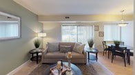 This single-floor residence at 14207 Grand Pre Road in Silver Spring, Maryland offers a well-organized layout with comfortable living spaces throughout. The living room is a welcoming focal point, featuring soft neutral and sage green accent walls, wood-look flooring, and large windows dressed with vertical blinds that invite generous natural light. An adjacent dining area provides a cozy space for meals, accented by a pendant light fixture and additional window views.

The kitchen is equipped with warm wood cabinetry, dark granite countertops, black appliances including a range with overhead microwave, and ample storage — offering both style and functionality. The bedrooms feature plush carpeting, sliding mirrored closet doors, and windows that bring in natural light, providing comfortable and well-proportioned retreats.

The bathrooms are finished with dark granite countertops and undermount sinks. One bathroom includes a full tub and shower combo, wood-toned cabinetry, and wood-look flooring, while a second bath features a sleek vanity with large mirror and updated lighting. Throughout the home, the consistent use of neutral tones and quality finishes creates a cohesive and practical living environment ideal for everyday comfort.