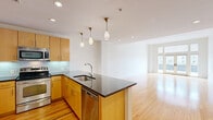 Located on the 8th floor at 230 N 6th St in downtown Richmond, VA, this well-appointed one-bedroom, two-bathroom apartment offers a thoughtfully designed layout with a clean, modern aesthetic. The open-concept living and kitchen area is anchored by warm hardwood flooring that flows throughout, creating a bright and cohesive atmosphere. Large French doors and expansive windows in the living room flood the space with natural light while providing sweeping city views. The kitchen features warm maple cabinetry, stainless steel appliances including a refrigerator, range, microwave, and dishwasher, dark granite countertops, a glass tile backsplash, and elegant pendant lighting. A peninsula with additional counter space seamlessly connects the kitchen to the living area. The spacious bedroom is carpeted for comfort, offers elevated city views through a generous window, and connects to a walk-in closet with built-in wire shelving. The bathrooms include a striking shower finished in dark slate-style tile with chrome fixtures. A dedicated laundry room with a stacked washer and dryer adds everyday convenience. Recessed lighting and clean white walls throughout contribute to the unit's bright, contemporary feel.