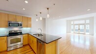 Located on the 8th floor at 230 N 6th St in downtown Richmond, VA, this well-appointed one-bedroom, two-bathroom apartment offers a thoughtfully designed layout with a clean, modern aesthetic. The open-concept living and kitchen area is anchored by warm hardwood flooring that flows throughout, creating a bright and cohesive atmosphere. Large French doors and expansive windows in the living room flood the space with natural light while providing sweeping city views. The kitchen features warm maple cabinetry, stainless steel appliances including a refrigerator, range, microwave, and dishwasher, dark granite countertops, a glass tile backsplash, and elegant pendant lighting. A peninsula with additional counter space seamlessly connects the kitchen to the living area. The spacious bedroom is carpeted for comfort, offers elevated city views through a generous window, and connects to a walk-in closet with built-in wire shelving. The bathrooms include a striking shower finished in dark slate-style tile with chrome fixtures. A dedicated laundry room with a stacked washer and dryer adds everyday convenience. Recessed lighting and clean white walls throughout contribute to the unit's bright, contemporary feel.