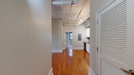 Located at 211 Union St, Unit 803 in the heart of downtown Nashville, Tennessee, this two-bedroom, one-bathroom residence offers a compact yet functional layout with distinctive urban character. Warm hardwood floors run throughout the main living areas and both bedrooms, providing a cohesive and inviting feel across the entire unit. The kitchen showcases an industrial-loft aesthetic, with exposed ductwork overhead, white cabinetry with open shelving, a full suite of black appliances including a dishwasher, electric range, and refrigerator, and a double-basin sink — all set against rich hardwood flooring. The two bedrooms are well-proportioned, each featuring large windows with blinds that frame views of the surrounding Nashville cityscape, allowing for ample natural light. Crown molding and clean white baseboards add a classic architectural touch to the rooms. The primary bedroom includes a louvered double-door closet for organized storage. The bathroom offers a white vanity with a dark countertop, an undermount sink, and neutral tile flooring. The overall ambiance of this unit blends classic building character with practical urban living, making it an ideal home in one of Nashville's most vibrant downtown locations.