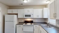 Located at 5212 Tern Pl in Fayetteville, NC, this two-story home offers a practical and well-organized layout across both levels. The kitchen is a standout functional space, featuring white cabinetry with brushed nickel hardware, dark countertops, and white appliances including an electric range, over-the-range microwave, refrigerator, and dishwasher. A double-basin stainless steel sink sits beneath a window, allowing natural light into the space. Wood-look plank flooring runs through the kitchen and several main-level rooms, providing a clean, cohesive look.

The bedrooms are carpeted and finished in neutral tones, creating a comfortable and versatile environment. One bedroom features a ceiling fan, large windows with natural views, and a reach-in closet with wire shelving. Additional rooms offer wood-look flooring and connect fluidly to the rest of the layout.

The bathrooms are well-appointed with white vanities, gray countertops, and full tub/shower combinations fitted with curved or straight curtain rods. Chrome and brushed nickel fixtures are consistent throughout, adding a uniform, polished detail. Textured ceilings are present throughout the home, complementing the overall straightforward and functional design aesthetic.