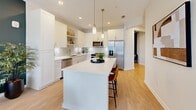 Located at 375 Summer Cypress Cove in Longwood, FL, this well-appointed one-bedroom, one-bathroom residence offers a thoughtfully designed single-floor layout with a bright, modern aesthetic. The open-concept main living area seamlessly combines the kitchen, dining, and living spaces. The kitchen is a standout feature, boasting white shaker cabinetry, a light subway tile backsplash, stainless steel appliances, under-cabinet lighting, open shelving, and a large center island with pendant lighting — perfect for both cooking and casual dining. Light wood-look flooring flows throughout, enhancing the airy feel of the space. The bedroom is generously sized, featuring multiple windows with natural light and ample room for large furnishings, complemented by three closets including a spacious walk-in with wire shelving. A dedicated office provides a productive work-from-home space, highlighted by a bold accent wall. The full bathroom features a white vanity with gold-tone hardware, wood-look flooring, and a tub-shower combo. Additional conveniences include an in-unit laundry area and a private balcony offering outdoor views of the lush, landscaped surroundings typical of Central Florida.