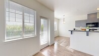 This single-story, 2-bedroom, 3-bathroom residence is designed for comfortable, efficient living. The open kitchen features sleek gray cabinetry with dark countertops, stainless steel appliances, and flows seamlessly into a bright dining area illuminated by a stylish pendant light. Large windows dressed with horizontal blinds fill the space with natural light and offer views of the surrounding neighborhood.

The living and dining areas feature light wood-look flooring, creating a clean, cohesive aesthetic throughout the common spaces. Both bedrooms are carpeted for added comfort. The primary bedroom is a well-sized retreat equipped with a ceiling fan, a wall-mounted HVAC unit, and a window for natural light. The second bedroom is similarly bright with a large window and carpeted flooring. Each bedroom benefits from dedicated closet space, including a walk-in closet with built-in shelving and hanging rods.

The bathrooms maintain the modern design language of the home, featuring gray vanities with dark countertops, geometric tile flooring, and well-lit mirrors. One bathroom includes a shower-tub combination. Throughout, the space is finished with clean white walls, panel-style doors with brushed nickel hardware, and consistent trim details that tie the design together cohesively.