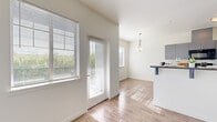 This single-story, 2-bedroom, 3-bathroom residence is designed for comfortable, efficient living. The open kitchen features sleek gray cabinetry with dark countertops, stainless steel appliances, and flows seamlessly into a bright dining area illuminated by a stylish pendant light. Large windows dressed with horizontal blinds fill the space with natural light and offer views of the surrounding neighborhood.

The living and dining areas feature light wood-look flooring, creating a clean, cohesive aesthetic throughout the common spaces. Both bedrooms are carpeted for added comfort. The primary bedroom is a well-sized retreat equipped with a ceiling fan, a wall-mounted HVAC unit, and a window for natural light. The second bedroom is similarly bright with a large window and carpeted flooring. Each bedroom benefits from dedicated closet space, including a walk-in closet with built-in shelving and hanging rods.

The bathrooms maintain the modern design language of the home, featuring gray vanities with dark countertops, geometric tile flooring, and well-lit mirrors. One bathroom includes a shower-tub combination. Throughout, the space is finished with clean white walls, panel-style doors with brushed nickel hardware, and consistent trim details that tie the design together cohesively.
