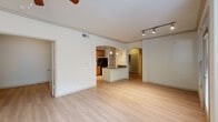Located at 8200 Main St in Houston, TX, this 2-bedroom, 1-bathroom single-floor residence offers a well-designed layout with consistent light wood flooring and neutral tones throughout. A welcoming entryway with natural light from a sidelight door transitions into a hallway framed by an elegant arched opening, connecting to the main living areas.

The spacious living room is illuminated by large windows with outdoor greenery views and features crown molding and a ceiling fan. Track lighting overhead adds a modern touch. An arched pass-through connects the living space to the kitchen, which is equipped with warm honey-toned cabinetry, dark granite countertops, black appliances including a refrigerator, range, and microwave, and a peninsula island with a stainless steel sink and pendant lighting above.

The primary bedroom is generously sized, featuring a ceiling fan and broad window, while the second bedroom offers similar light wood flooring and a dedicated window. A walk-in closet with built-in wire shelving and organization systems serves the primary suite. The bathroom includes a tiled soaking tub set within an arched niche, wood-toned cabinetry, and granite counters, completing this cohesive and functional home.