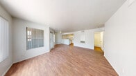 Located at 3651 N Rancho Dr in Las Vegas, NV, this single-floor residence offers three bedrooms and two bathrooms across a well-organized layout. The open-concept living and dining area is a standout feature, showcasing warm wood-look flooring, a textured ceiling, and large windows dressed with vertical blinds that allow ample natural light to fill the space. The kitchen is positioned at the heart of the home, featuring a convenient peninsula with counter seating, white cabinetry, a full suite of white appliances including a refrigerator and electric range, and a bright overhead light panel that adds a warm glow. The spacious primary bedroom includes a closet and exterior-facing windows with outdoor views. The additional bedrooms are well-proportioned, each with wood-look flooring and windows that bring in natural light. Both bathrooms are finished consistently with white cabinetry, granite-style countertops, a single vanity sink, and a full tub-shower combination with white tile surround. Wood-look flooring carries throughout the bathrooms as well, maintaining a cohesive aesthetic. A hallway connects the private areas of the home, and the overall design emphasizes a clean, neutral palette throughout.