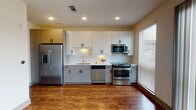 This well-appointed single-floor unit offers a thoughtfully designed layout that balances modern aesthetics with everyday functionality. The kitchen serves as a standout feature, showcasing two-tone cabinetry with upper white panels and lower light wood-grain bases, complemented by sleek bar-pull hardware. A striking herringbone-patterned tile backsplash adds visual interest behind the countertops, while a full suite of stainless steel appliances — including a French door refrigerator with ice dispenser, gas range, over-the-range microwave, and dishwasher — ensures a complete and contemporary cooking experience. Recessed lighting illuminates the space, and a large window with blinds allows natural light to pour in. Warm hardwood-style flooring flows consistently throughout the main living areas and into the hallway, creating a cohesive and inviting atmosphere. The bathroom features light large-format tile flooring, a wood-grain vanity with a white countertop, and a clean, minimal design. A spacious room with sliding glass doors opens directly to a private balcony, offering refreshing natural light and pleasant views of surrounding greenery — a bright and airy retreat within the unit.