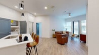 This thoughtfully designed 2-bedroom, 3-bathroom residence offers a comfortable and functional single-floor layout. The open-concept kitchen and living area serves as the heart of the home, featuring light wood-style flooring that flows throughout the main space. The kitchen is outfitted with crisp white cabinetry, a blue tile backsplash, stainless steel appliances including a French door refrigerator and range, and a large center island with a built-in sink and seating for three — ideal for casual dining and entertaining. Pendant lighting overhead adds a modern touch. The adjoining living room is bright and airy, with tall ceilings, a ceiling fan, and large windows that invite abundant natural light and outdoor views. The bedrooms are carpeted for comfort, each offering multiple windows, ceiling fans, and a calm, neutral palette. The primary bedroom provides a generous footprint with ample room for furnishings. The bathrooms are finished with granite-topped vanities, brushed nickel fixtures, and glass-enclosed walk-in showers clad in elegant marble-style tile. A dedicated laundry room and two closets add to the unit's practical appeal, rounding out this well-appointed residence.