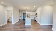 Located at 4405 River Creek Rd in Mason, Ohio, this well-appointed 2-bedroom, 2-bathroom residence offers a thoughtfully designed single-floor layout with modern finishes throughout. The open-concept kitchen and living area serves as the heart of the home, anchored by a large center island with a quartz countertop, undermount sink, and matte black fixtures. White shaker cabinetry, stainless steel appliances, and recessed lighting complement the contemporary aesthetic, while a striking sculptural pendant light adds a designer touch. Rich wood-tone flooring flows seamlessly throughout the space, grounding the light gray walls and white trim. French doors in the living area invite natural light and lead to a private balcony with open views of the surrounding Mason streetscape and greenery. Both bedrooms are generously proportioned, each featuring ceiling fans, neutral tones, and wood-look flooring. The primary bedroom offers direct access to an en-suite bathroom with a barn-style sliding door. The bathrooms are finished with white cabinetry, quartz countertops, and matte black hardware. Four closets, including walk-in storage with wire shelving, provide ample organization. A dedicated utility room rounds out this clean, move-in-ready home.