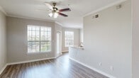 This thoughtfully designed 2-bedroom, 1-bathroom residence offers a comfortable and functional single-floor layout. The open-concept living and dining area is bright and welcoming, featuring wood-style plank flooring, neutral-toned walls, crown molding, and ceiling fans with light fixtures. Large windows allow generous natural light to fill the space, creating an airy atmosphere throughout.

The kitchen is a standout feature, equipped with warm honey-toned wood cabinetry, stainless steel appliances including a range, over-the-range microwave, dishwasher, and refrigerator, complemented by light countertops and a peninsula with a sink that opens toward the living area—ideal for both cooking and entertaining.

The primary bedroom is generously sized, offering a ceiling fan, hardwood-style flooring, and access to a walk-in closet complete with wire shelving and a freestanding shelving unit for organized storage. The bathroom features a dual-sink vanity with warm wood cabinetry, a large mirror, and a full soaking tub with tiled surround. An additional closet with built-in shelving provides extra storage convenience. The cohesive design and neutral palette throughout create a clean, move-in-ready environment.