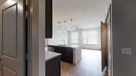 This single-floor residence offers a thoughtfully designed open-concept layout that seamlessly connects the kitchen, dining, and living areas. The kitchen is a standout feature, showcasing rich dark espresso cabinetry that extends to the ceiling, granite countertops, a white subway tile backsplash, and a full suite of stainless steel appliances including a range, microwave, and refrigerator. A central island with a built-in sink and pendant lighting above serves as both a functional workspace and a natural gathering point. The adjoining living area is bright and airy, benefiting from multiple windows dressed with horizontal blinds and a ceiling fan that promotes comfortable airflow.

The residence includes multiple bedrooms, each equipped with ceiling fans and natural light. The primary bedroom features wood-style flooring, while additional bedrooms are finished with plush carpet. Two bathrooms mirror the home's consistent design language, each outfitted with dark-framed vanity mirrors, granite-topped dark cabinetry with undermount sinks, and chrome fixtures. Wood-style flooring flows throughout the main living areas, tying the space together with a clean, contemporary aesthetic. The overall palette of neutral tones and modern finishes creates a polished and welcoming atmosphere throughout.