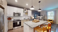 Located in Kingston, MA, this thoughtfully designed single-floor residence offers a cohesive blend of modern finishes and comfortable living. The open-concept kitchen is a standout feature, showcasing granite countertops, a large center island with bar seating illuminated by pendant lighting, two-tone cabinetry pairing white uppers with light wood lowers, a white subway tile backsplash, and a full suite of stainless steel appliances. The kitchen flows seamlessly into the living area, which features rich hardwood-style flooring, a bold dark accent wall, and large windows that draw in generous natural light. A private door provides direct outdoor access from the living space. The two bedrooms are well-appointed and serene, each with hardwood-style flooring, ample natural light from large windows, and ceiling fans. The primary bedroom includes a spacious walk-in closet outfitted with wire shelving and hanging rods for organized storage. The bathroom features a subway-tiled soaking tub and shower combination, a granite-topped vanity with light wood cabinetry, and a large framed mirror. Recessed lighting throughout the home ensures a bright, polished ambiance in every room.
