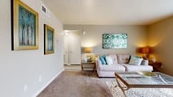 Located at 6000 W 70th St in Shreveport, Louisiana, this 2-bedroom, 1-bathroom residence offers a practical and comfortable single-floor layout thoughtfully designed to maximize its living space. The combined living and dining area serves as the heart of the home, featuring warm neutral-toned carpet, a large window with vertical blinds that invites natural light, and a welcoming entryway accented with a decorative console table and mirror. The living room provides a cozy setting with clean lines and easy access to the hallway and adjacent rooms. The kitchen is equipped with stainless steel appliances, including a full-size refrigerator, white cabinetry with light stone countertops, and wood-look tile flooring that adds a modern touch. The dining area transitions seamlessly from the kitchen, featuring hardwood-style flooring and textured wall detailing with chair rail molding. Both bedrooms are carpeted and offer a restful atmosphere; the primary bedroom features a ceiling fan, a generously sized window for natural light, and ample floor space. The bathroom includes a full-size soaking tub and shower combination with clean white surroundings. A connecting hallway ties all rooms together efficiently, completing this functional and well-maintained home.