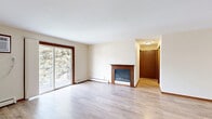 This 2-bedroom, 1-bathroom unit in Madison, WI offers a well-organized single-floor layout with a clean, neutral aesthetic throughout. Light wood laminate flooring runs continuously across all rooms, complemented by warm wood-toned trim and doors that add a consistent design element.

The spacious living room is a standout feature, anchored by a fireplace and bathed in natural light from a sliding glass door that opens to a private balcony overlooking lush greenery. Baseboard heating and a wall-mounted air conditioning unit ensure year-round comfort.

The galley-style kitchen is thoughtfully designed with rich wood cabinetry, light stone-finish countertops, a white subway tile backsplash, and a full suite of stainless steel appliances including a refrigerator, electric range, microwave, and dishwasher.

Both bedrooms are comfortably sized with light-filled windows, baseboard heating, and light wood flooring. The primary bedroom features a double sliding-door closet, providing ample storage. The second bedroom also offers closet access and peaceful outdoor views.

The full bathroom is finished with warm wood cabinetry, a light stone countertop, a large vanity mirror, and a tub-shower combo, all set on neutral tile flooring. The overall space offers a functional, move-in-ready environment in a convenient Madison location.