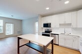 Located at 2320 Clubhouse Station Pl in Waldorf, Maryland, this single-floor, 2-bedroom, 2-bathroom residence offers a well-designed layout with modern finishes throughout. The open-concept living, dining, and kitchen area serves as the heart of the home, providing a seamless flow between spaces. The kitchen is outfitted with white shaker-style cabinetry, quartz countertops, a subway tile backsplash, stainless steel appliances including a range, microwave, and dishwasher, and a undermount sink. Light hardwood flooring runs throughout the unit, adding warmth and continuity to each room. Both bedrooms are generously proportioned, filled with natural light from large windows offering exterior views, and include dedicated closet space. The primary bedroom is notably spacious and features its own closet. Each bathroom is finished with white vanity cabinetry, quartz countertops, large mirrors, and hardwood-style flooring, with one bathroom featuring a walk-in shower. Additional highlights include a private balcony, an in-unit laundry area, three closets for ample storage, and recessed lighting throughout. The overall aesthetic is clean, contemporary, and move-in ready.