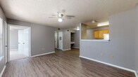 Located at 401 Second St in Conway, Arkansas, this single-floor unit offers a practical and cohesive layout designed for comfortable everyday living. The interior is unified by neutral gray walls, white trim, and a textured popcorn ceiling throughout.

The open living area is finished with durable wood-look vinyl plank flooring and is fitted with a ceiling fan for year-round comfort. A half-wall partition separates the living space from the adjacent kitchen, which features warm honey-toned wood cabinetry, white countertops, and black appliances including an electric range, refrigerator, and dishwasher. The galley-style kitchen provides ample cabinet and counter space along both walls.

The bedrooms are carpeted and each equipped with ceiling fans and closets offering built-in shelving and hanging rods. The primary bedroom includes two closets, providing generous storage. The bathrooms are simply appointed, featuring a full soaking tub with a clean white surround and wood cabinetry above for additional storage.

Natural light filters into the living area through a window fitted with blinds. The floor plan, visible in the dollhouse view, reveals a well-organized layout that efficiently connects the main living spaces, bedrooms, and bathrooms in a single-story configuration.
