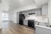 Located at 2442 Barry Ave in Los Angeles, CA, this well-designed one-bedroom, one-bathroom unit offers a clean, modern aesthetic with thoughtful finishes throughout. The open-concept layout connects the kitchen and living area seamlessly, maximizing the efficient use of space. The kitchen is a standout feature, equipped with sleek gray flat-front cabinetry extending to the ceiling for ample storage, light-colored countertops, a full suite of black appliances including a refrigerator, electric range with hood, and a dedicated sink workspace. Wood-look plank flooring runs throughout the main living areas, adding warmth to the contemporary design. The bedroom is a comfortable, well-proportioned space bathed in natural light from a large window with vertical blinds, offering a bright and airy atmosphere. Two closets provide convenient storage options. The bathroom is spacious and accessibility-friendly, featuring grab bars, a wide-open floor plan, and neutral tile flooring, making it both functional and inclusive. Crisp white walls and recessed lighting contribute to the clean, minimalist ambiance of the unit. Situated in the desirable West Los Angeles neighborhood, this unit combines practical design with modern style.