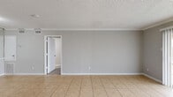 Located at 10301 Sandpiper Dr in Houston, TX, this one-bedroom, two-bathroom unit offers a practical and efficient single-floor layout. Light gray walls, white crown molding, and textured ceilings are consistent throughout, creating a cohesive and clean aesthetic. The living room is finished with neutral tile flooring and features a sliding glass door fitted with vertical blinds that opens to a patio with views of the surrounding community. Adjacent to the living area, the dining room shares the same open tile flooring and connects seamlessly to the kitchen. The kitchen is well-appointed with white cabinetry, granite-style countertops, a double sink, and black appliances including a refrigerator, range, microwave, and dishwasher. A built-in bookshelf adds functional storage near the main living area. The spacious bedroom is carpeted for comfort, includes a ceiling fan with lighting, a window for natural light, and direct access to a closet as well as an en-suite bathroom. In total, three closets provide generous storage throughout the unit. Both bathrooms feature tile-surround tub and shower combinations. The patio overlooks a gated community with ample parking.