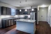 This single-story 1-bedroom, 1-bathroom flex unit in Memphis, TN offers a thoughtfully designed layout with modern finishes throughout. Rich hardwood flooring flows through the main living areas, creating a warm and cohesive aesthetic from entry to living space.

The kitchen is a standout feature, showcasing dark espresso cabinetry paired with granite countertops, a large central island with white cabinetry beneath, stainless steel appliances including a refrigerator, range, microwave, and dishwasher, and pendant lighting that adds a refined touch. Multiple windows allow natural light to fill the space, with views of surrounding greenery.

The flex room offers versatility, featuring neutral walls, hardwood flooring, and dual windows that bring in additional natural light — suitable as a home office, den, or secondary living area. The bedroom is generously sized with plush carpeting, a ceiling fan, and a window that brightens the room naturally.

The bathroom is efficiently designed with hardwood flooring and direct access to a walk-in closet equipped with wire shelving for organized storage. Neutral tones and clean lines throughout the unit contribute to a bright, move-in-ready atmosphere that balances comfort with functional, modern living.