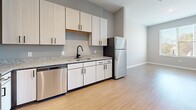 Located at 6228 Nolensville Pike in Nashville, TN, this single-floor unit offers a thoughtfully designed layout with modern finishes throughout. The open-concept living area features warm wood-look luxury vinyl plank flooring that flows seamlessly through the main spaces, complemented by neutral gray walls and clean white trim that create a bright, contemporary atmosphere.

The kitchen is a functional highlight, outfitted with light wood cabinetry, black hardware accents, granite countertops, and a full suite of stainless steel appliances including a refrigerator, dishwasher, range, and microwave. A black matte faucet over a single-basin sink adds a stylish, modern touch.

The bedroom offers plush carpeting, soft neutral tones, and a generously sized window that invites natural light and provides views of the surrounding greenery, contributing to a calm and comfortable environment.

The bathroom is finished with wood-look vinyl flooring consistent with the rest of the unit, granite-topped vanity, and crisp white doors with black hardware detailing. Ample closet access is conveniently located nearby.

Throughout the space, recessed lighting, track lighting, and ceiling vents reflect a well-considered and functional design. The overall aesthetic is clean, contemporary, and move-in ready, offering a comfortable living environment in a convenient Nashville location.