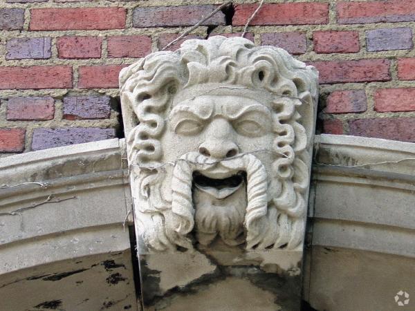 Close-up of stone face reveals a vine across the nose may be responsible for his facial expression - Judson Manor