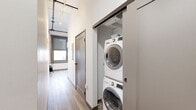 Located on the 7th floor of 305 Michigan Ave in the heart of downtown Detroit, this efficiently designed studio offers a smart, modern layout that maximizes every square foot. The open-plan living, dining, and kitchen area serves as the heart of the unit, where wood-toned flooring, neutral gray tones, and contemporary finishes create a cohesive, urban aesthetic. Large windows with roller shades flood the space with natural light while framing impressive views of Detroit's downtown skyline — a standout feature of the unit. The bedroom area is well-appointed, featuring a ceiling fan with a wall-mounted mini-split system for year-round climate control, stylish sconce lighting, and vibrant wall art that adds a creative flair to the space. A hallway connects the living area to a clean, functional bathroom finished in white tones with wood-look flooring. A dedicated closet provides storage, while a conveniently tucked in-unit laundry closet houses a full stacked washer and dryer — a practical amenity rarely found in compact urban residences. Track lighting in the hallway and an overall clean, contemporary design make this unit a polished downtown Detroit retreat.