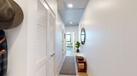 Located in Chicago's dynamic Fulton Market neighborhood, this two-bedroom, two-bathroom residence offers a refined urban living experience defined by modern industrial design. Exposed concrete ceilings contrast beautifully with crisp white walls and light-toned hardwood flooring throughout, creating a contemporary aesthetic that feels both stylish and welcoming. The entry hallway sets an organized tone, featuring louvered closet doors and recessed lighting. The open-concept living room is a standout, wrapped in floor-to-ceiling black-framed windows that frame sweeping panoramic views of the Chicago skyline, flooding the space with abundant natural light and providing direct access to a balcony. The kitchen runs parallel to the living area and is equipped with two-tone cabinetry, a sleek white quartz countertop, matte black fixtures, stainless steel appliances, and its own window with city views. The primary bedroom is a calm retreat with an exposed concrete ceiling, a walk-in closet, and warm wood flooring. The second bedroom offers built-in closet storage. Both bathrooms are finished with clean, modern tile work, floating dark-toned vanities, illuminated mirrors, and matte black hardware — one featuring a soaking tub and the other a glass-enclosed walk-in shower.
