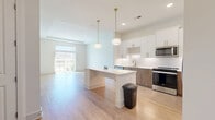 Located in Chamblee, GA, this well-designed 2-bedroom, 2-bathroom single-story residence offers a thoughtfully planned open-concept layout that maximizes comfort and functionality. Light hardwood-style flooring flows throughout the main living areas, creating a bright, cohesive aesthetic.

The kitchen is a standout feature, boasting two-tone cabinetry — white uppers paired with warm wood-grain lowers — accented by gold hardware and a geometric tile backsplash. Stainless steel appliances, including a French door refrigerator, electric range, and built-in microwave, complement the clean white countertops. A central island with pendant lighting connects seamlessly to the open living room, which benefits from abundant natural light through a large sliding glass door leading to the outdoors.

The generously sized primary bedroom features plush carpeting, natural light from exterior windows, and access to a private en-suite bathroom with a walk-in shower and white vanity. A dedicated walk-in closet with wire shelving adds practical storage. The second bedroom is equally well-appointed with carpeted flooring and bright windows. The second bathroom features a full tub-shower combo, white vanity, and wood-framed mirror. Clean, neutral tones throughout the space contribute to a calm and modern ambiance.