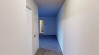 This single-story home offers a thoughtfully arranged layout with four bedrooms, two bathrooms, a kitchen, two hallways, and a closet — all contained within a compact and efficient floor plan. The bedrooms are carpeted throughout, with the generously sized primary bedroom featuring a window that invites natural light and includes a built-in closet with louvered bifold doors. The additional bedrooms are similarly carpeted, with some featuring ceiling fans with integrated light fixtures and windows overlooking the outdoors. The kitchen is equipped with warm wood-toned cabinetry, ample upper and lower storage, a sink, dishwasher, electric range, and a full-size refrigerator, all set on hardwood-style flooring. A pass-through window with built-in cabinetry connects the kitchen area to an adjoining space, adding a functional and classic design detail. The two bathrooms are finished with hardwood-style flooring, warm wood vanity cabinetry, and white countertops. One bathroom features a shower-tub combination, while the other offers a walk-in shower with sliding glass doors. The hallways are carpeted and painted in soft blue tones, providing smooth transitions between rooms. Overall, the home presents a clean, functional, and neutral aesthetic suitable for a variety of living arrangements.