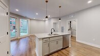 Located at 199 Dickenson St in Columbus, OH, this well-appointed 2-bedroom, 1-bathroom residence offers a thoughtfully designed single-floor layout with modern finishes throughout. The open-concept living and kitchen area is anchored by a central island featuring granite countertops, an undermount sink with a matte black faucet, and stylish pendant lighting overhead. The kitchen is fully equipped with stainless steel appliances, including a refrigerator, range, microwave, and dishwasher, complemented by gray shaker-style cabinetry and a tile backsplash. Light hardwood flooring flows through the main living areas, enhancing the bright, airy atmosphere. The spacious living room receives generous natural light through large windows that offer outdoor views. Both bedrooms are carpeted and finished with neutral tones, providing a comfortable and quiet retreat. The full bathroom showcases large-format marble-style tile flooring, a granite-topped vanity with a black-accented mirror and fixtures, and a glass-enclosed shower with striking black tile detailing. Additional features include a dedicated utility room and closet. Recessed lighting throughout maintains a clean, contemporary aesthetic across the entire space.