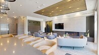 Located at 200 Rood Ave in Grand Junction, Colorado, this generously sized amenity floor offers a curated collection of resident-focused spaces designed with modern sophistication. The pool lounge serves as the centerpiece, featuring a striking slatted wood ceiling with integrated lighting, a floor-to-ceiling tile-clad fireplace wall with an embedded flat-screen TV, and a linear gas fireplace. Seating includes curved lounge chairs, sculptural stone coffee tables, and a tufted accent wall, all complemented by rich olive green and neutral tones. A wet bar area with grid-pattern tile, floating shelves, and warm caramel leather bar stools provides a refined social hub. The fitness center is expansive and well-lit, benefiting from large floor-to-ceiling windows that invite natural light and outdoor views. It is outfitted with a full array of cardio machines, strength equipment, free weights, resistance tools, and exercise balls, with full-length mirrors and vibrant superhero-themed artwork adding energy to the space. The entry corridor features terrazzo flooring, curated wall art, a geometric mural accent wall, and a sleek stainless steel elevator. A dedicated package locker area with smart parcel lockers and individual mailboxes ensures convenient resident services. Bike storage rounds out the amenity offerings.