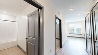 Located at 944 Broadcast Pl in Jacksonville, FL, this thoughtfully designed single-floor unit offers a clean, contemporary aesthetic throughout. The open-concept kitchen and living area serves as the heart of the space, bathed in natural light from multiple large windows dressed with horizontal blinds. The kitchen is well-appointed with two-tone cabinetry — white upper cabinets and gray lower cabinets — complemented by a subway tile backsplash, light quartz countertops, a matte black faucet, and a full suite of stainless steel appliances including a refrigerator, range, dishwasher, and microwave. Light wood-look flooring runs throughout the main living areas, lending a warm and modern feel. A central hallway connects the living space to the private areas of the unit, lined with stylish gray panel doors trimmed in dark frames. The carpeted bedroom offers a ceiling fan, generous proportions, and access to two closets, providing ample storage. The full bathroom features gray shaker-style vanity cabinetry, a white quartz countertop, a framed mirror, matte black fixtures, and a tiled tub-shower combination. A dedicated laundry area rounds out the unit's practical amenities, making this a fully functional and polished living space.
