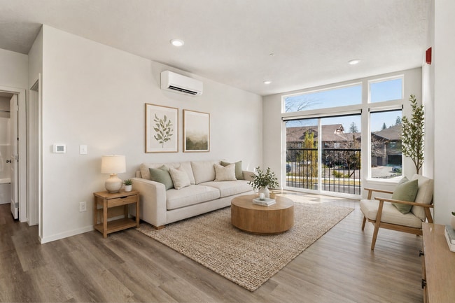 Bright and inviting living room with large windows and natural sunlight. - Lofts at Garden District