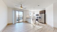 Located at 2818 Cullman Ave in Charlotte's 28206 neighborhood, this single-floor unit showcases a clean, contemporary design with an open-concept layout that seamlessly connects the living and kitchen areas. Light-toned hardwood-style flooring runs throughout the main living spaces, enhancing the bright, airy atmosphere created by abundant natural light. A ceiling fan with a brass accent fixture anchors the living area, which flows directly to a private balcony through a sliding glass door, offering outdoor access and views of the surrounding neighborhood.

The kitchen is well-appointed with stainless steel appliances, including a refrigerator, electric range, and over-the-range microwave. A granite-topped island with pendant lighting serves as a central workspace and casual dining area, complemented by white upper cabinetry, dark lower cabinetry, and a subway tile backsplash.

The bedrooms feature plush carpeting, ceiling fans, and well-sized windows fitted with blinds that allow for natural light and privacy. Closet storage is included in the bedrooms.

The bathrooms are finished with wood-toned vanity cabinetry, granite countertops, and light wood-look tile flooring. One bathroom includes a full soaking tub with a tiled surround, while another features a vanity with separate water closet, offering a functional and refined design throughout.