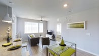 Located at 1420 Renaissance Drive in Longmont, Colorado, this single-floor space offers a well-designed, modern interior that balances comfort and functionality. The open-concept layout seamlessly connects the living and dining areas, creating a spacious and airy feel throughout. Light gray walls and smooth ceilings complement the light wood-tone flooring, lending the space a clean and contemporary look. A ceiling fan is centrally positioned in the living area, enhancing both airflow and style. Large windows with vertical blinds flood the space with abundant natural light, contributing to the bright and welcoming atmosphere. The living area is thoughtfully arranged with a sofa and accent chairs, while a media console provides practical storage and entertainment options. The dining area features a glass-top table with vibrant green upholstered chairs, adding a bold pop of color against the otherwise neutral palette. Recessed lighting provides consistent, even illumination throughout. A glimpse into the adjacent bedroom reveals a continuation of the light, airy design ethos. The overall ambiance is modern and inviting, making this a well-appointed space suited for comfortable everyday living.