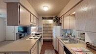 Located at 922 N Sidney Ave in Russellville, Arkansas, this single-floor residence offers a well-organized layout that makes efficient use of its space throughout. The galley-style kitchen is thoughtfully designed with ample light wood cabinetry on both sides, laminate countertops, a double-coil electric range, a dishwasher, and a stainless steel sink. A built-in open shelving pantry at the end of the kitchen provides generous storage, while wood-look flooring adds warmth underfoot. The living room is bright and inviting, featuring large windows that allow natural light to fill the carpeted space, complemented by a textured ceiling. Two well-proportioned bedrooms each feature ceiling fans with light fixtures, soft carpet flooring, textured ceilings, and windows that bring in natural light. The full bathroom is finished with wood-look flooring, a vanity with cabinetry, a combined tub and shower enclosed with a sliding glass door, and a toilet. A notable convenience is the in-unit laundry area, which accommodates a full-size washer and dryer stacked adjacent to the bathroom. Throughout the residence, neutral tones and textured ceilings create a cohesive, comfortable ambiance suitable for everyday living.